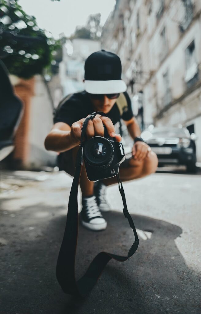person wearing black and gray cap holding DSLR camera